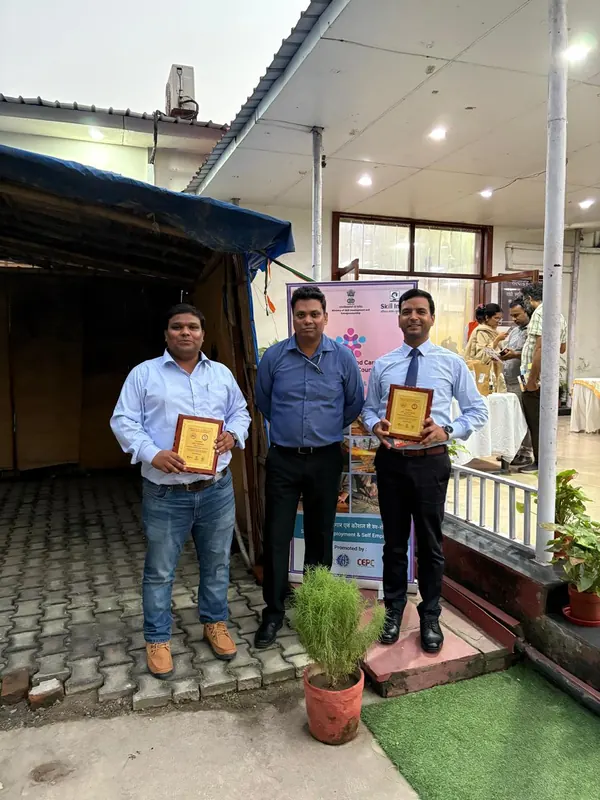 Award winners holding plaques beside an HCSSC standee